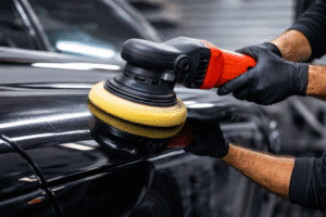 Professional car detailing expert performing exterior paint correction and polishing on a black car using a dual-action polisher.